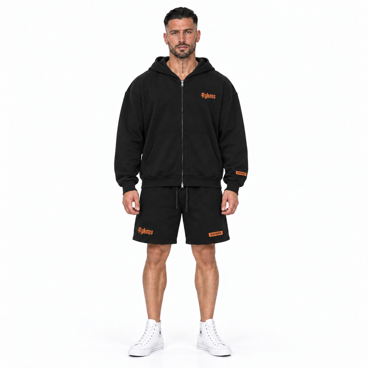 AYKONS [400] Solomon's Secrets Zip hoodie in black and orange - Model 1 straight front full-body shot with matching orange embroidered CERTIFIED shorts and all-white high-top Converse.